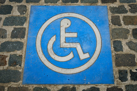 在鹅卵石停车场上设置残疾人停车标志。比利时安特卫普地面上的残疾人停车标志