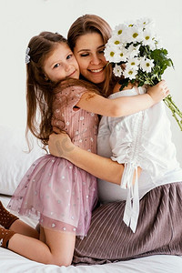 微笑的母亲女儿与花束春天的花朵