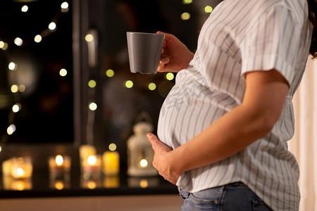 怀孕、圣诞节和人们的观念-孕妇晚上在家喝茶的特写。孕妇在家喝茶的特写