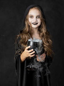 万圣节小女巫在酒杯里装着烟药。万圣节小女巫和药水
