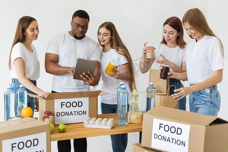 许多志愿者准备盒子与食物捐赠使用平板电脑