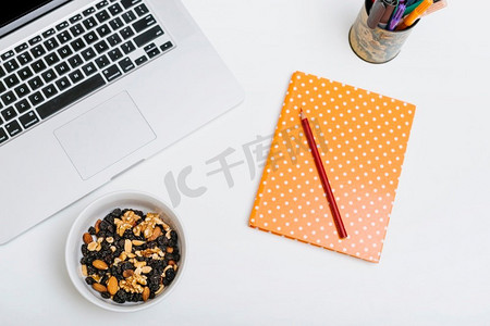 坚果食品背景摄影照片_彩色铅笔笔记本坚果食品笔记本电脑白色背景