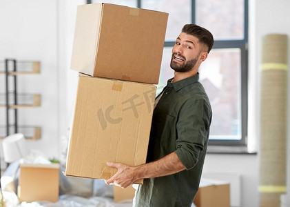 移动，人和房地产概念—愉快的微笑男子拿着盒子与东西在新家。快乐的人与盒子搬到新家