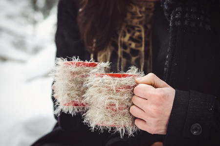围巾女摄影照片_一男一女穿着保暖的衣服，戴着围巾，在雪林和田野中散步