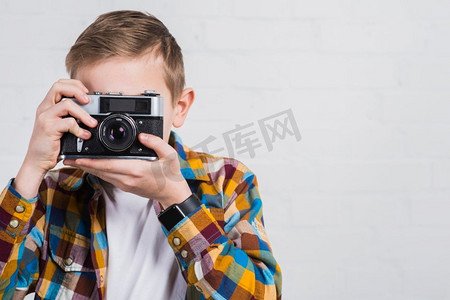 男孩拍照与老式相机反对白色背景