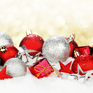 雪摄影照片_与美丽的装饰的圣诞卡在雪在金色背景。圣诞装饰在雪