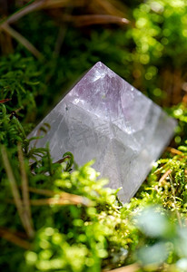 魔法晶体摄影照片_神秘的科学和超自然的概念—石英晶体金字塔特写镜头在苔藓在森林。在森林苔藓上的石英晶体金字塔