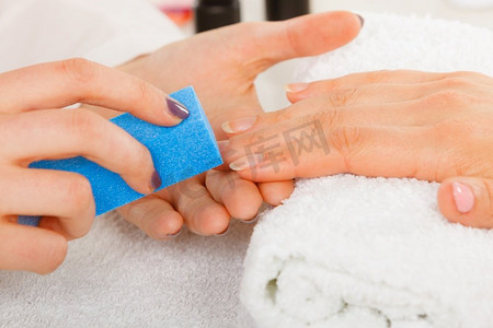 女人的手放在毛巾上，美容师锉指甲。美容养生水疗护理，美甲概念。妇女得到美甲做文件指甲