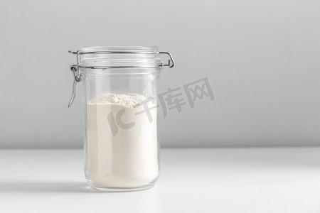 食物，饮食和烹饪概念-白色背景下加小麦面粉的罐子。白色桌子上放着面粉的罐子的特写