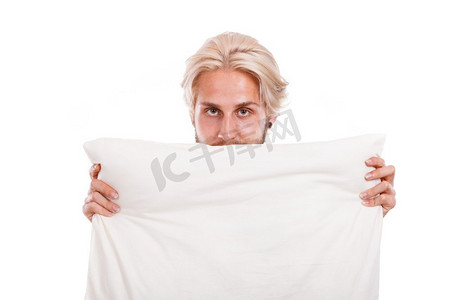 藏起来摄影照片_男人把脸藏在枕头后面，复制空间的文字，孤立在白色。男人用枕头盖住他的脸