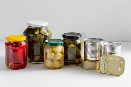 食物储存、食用和保存概念-将罐子和锡罐与餐桌上的保存物进行特写。罐子和锡罐与腌制食品的特写