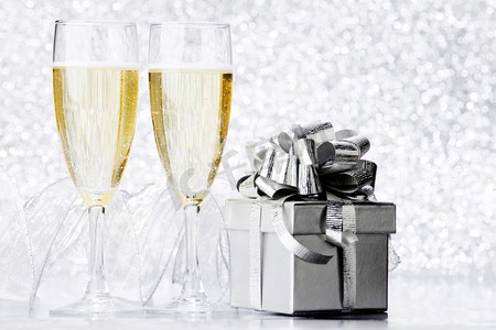 玻璃香槟和银礼物在闪光背景。香槟