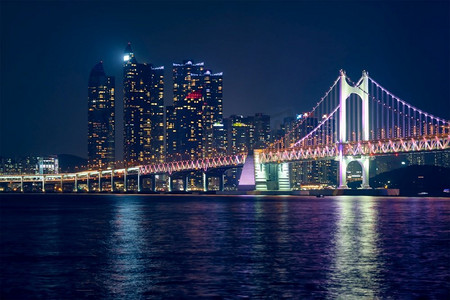 光岸大桥和摩天大楼在夜色中灯火通明。韩国釜山。光岸大桥和夜间的摩天大楼。韩国釜山