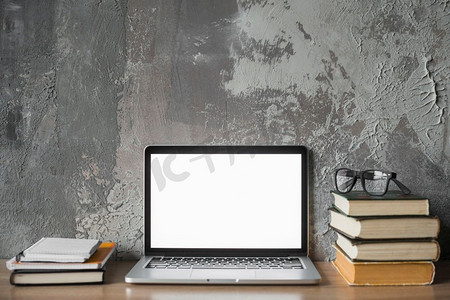 堆叠书籍眼镜笔记本电脑与空白白色屏幕木表面
