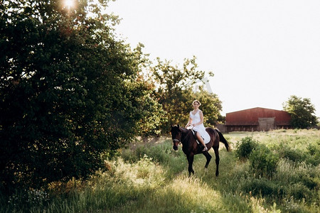 村路摄影照片_一个女孩在一个白色太阳裙散步与棕色的马在村庄