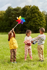 童年、休闲和人的概念快乐的孩子们在公园里玩风车。玩风车的快乐小朋友在公园玩得开心