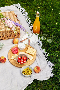 休闲和饮料概念-在草地上的野餐毯子上近距离放置食物、饮料和篮子。草地上野餐毯上的食物、饮料和篮子