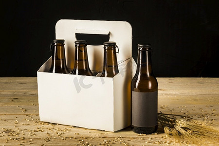 啤酒瓶纸箱和麦穗在木质表面 