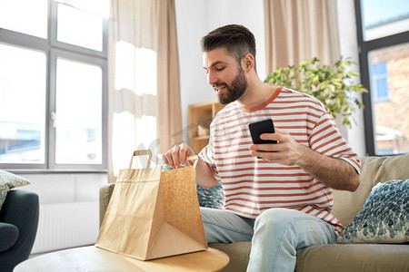 沟通、休闲和人的概念-男人在家里用智能手机叫外卖点餐。一名男子在家里用手机查看订餐情况