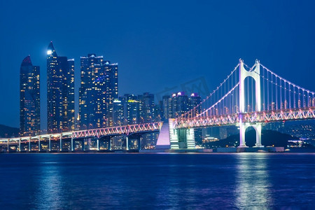 广安桥和摩天大楼在夜里被照亮。韩国釜山。夜晚的广安桥和摩天大楼。韩国釜山