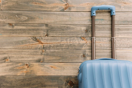 假期旅行行李箱摄影照片_蓝色旅行箱对木背景