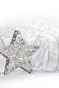 装饰银圣诞星和丝带在闪光背景。装饰圣诞星