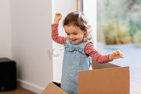 大气地产开盘摄影照片_童年，休闲和移动的概念—小女婴在家里玩纸箱。女婴在家里玩纸板箱
