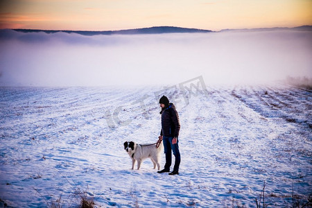 人与他的狗在雾冬天风景在日落