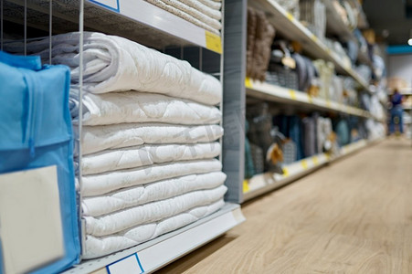 毯子堆放在货架上与价格标签在超市。床单堆在商店。选择性聚焦。铺在商店货架上的毯子选择性焦点
