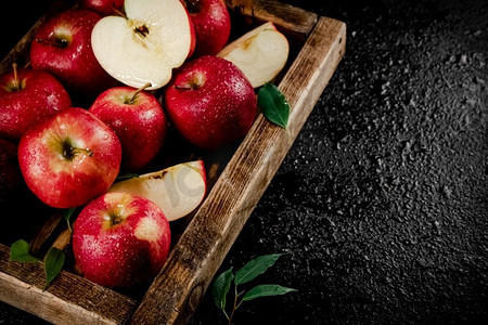 一个木托盘上的苹果碎片和整个红苹果。黑色背景。高质量的照片。一个木托盘上的苹果碎片和整个红苹果。 