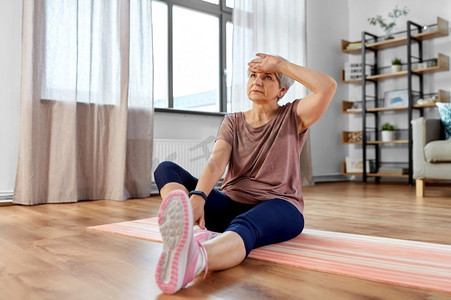 eld摄影照片_运动、健身和健康生活方式概念—疲惫的老年妇女在家里垫上锻炼。疲惫的高级妇女行使在垫在家里