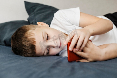 儿童躺床使用手机侧视图