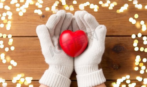 冬天,情人节和圣诞节的概念 — 双手戴着白色羊毛手套,在木板背景上拿