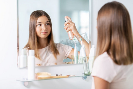 美与人的概念 — 十几岁的女孩在家里的浴室里照镜子并使用头发定型