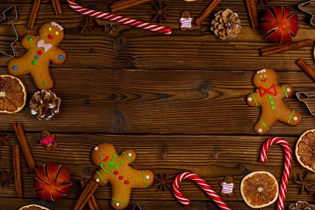 圣诞节标题框摄影照片_圣诞节木背景与小玩意儿，姜饼饼干糖果手杖和装饰。圣诞节木背景