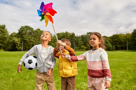 童年，休闲和人的概念—快乐的孩子在公园玩风车。快乐的孩子玩风车在公园