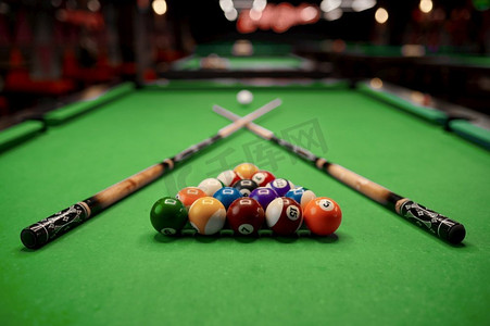台球桌上有三角形的彩色球和为游戏选择焦点准备的球杆。带彩球的台球桌