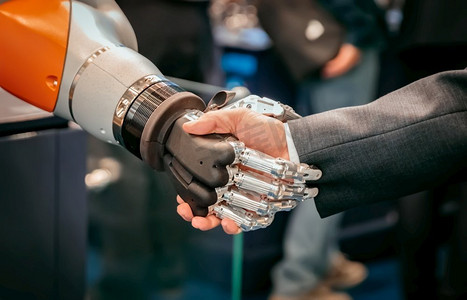 一个商人与Android机器人握手的手。人类与人工智能交互的概念。