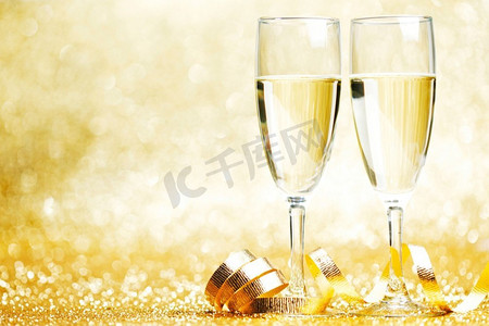 两杯金色背景上有蝴蝶结的香槟。香槟和蝴蝶结