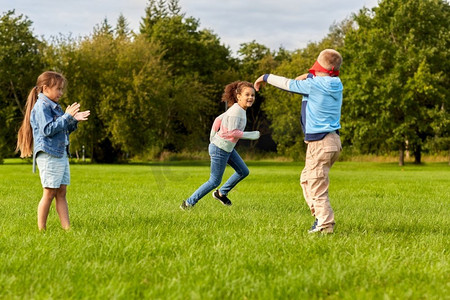 童年、休闲和人的概念-一群快乐的孩子在公园里玩捉迷藏游戏和跑步。快乐的孩子们在公园里玩耍和奔跑