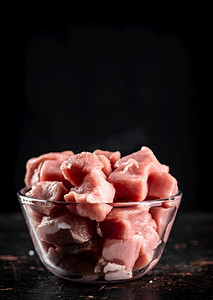 生猪肉放在玻璃碗里。黑色背景。高质量的照片。生猪肉放在玻璃碗里。