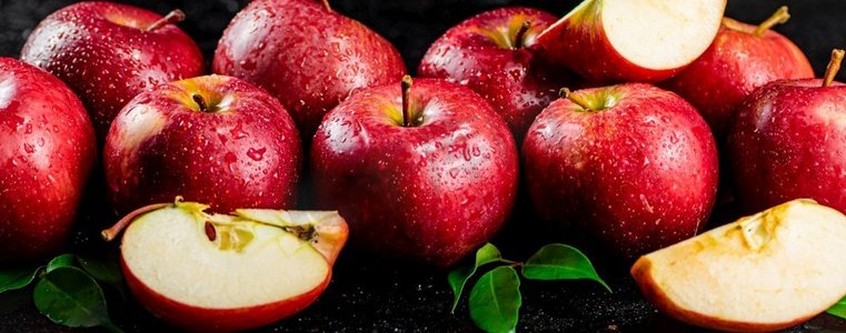 水果半个摄影照片_桌子上有半个和整个苹果，有叶子。黑色背景。高质量的照片。桌子上有半个和整个苹果，有叶子。