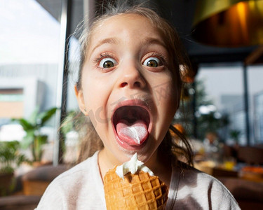 冰淇淋底纹摄影照片_惊讶的女孩吃冰淇淋关闭