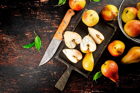 梨子背景摄影照片_切成片的新鲜梨子放在切菜板上。在黑暗的背景下。高质量的照片。切成片的新鲜梨子放在切菜板上。