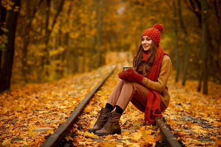 妇女美丽的秋天象象在森林或公园与橙色秋天叶子在模糊的背景。美丽的秋天肖像的妇女在森林