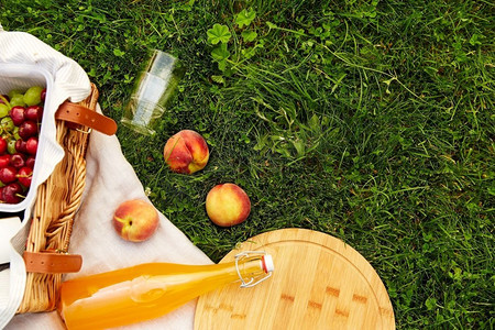 休闲和饮料概念-在草地上的野餐毯子上近距离放置食物、饮料和篮子。草地上野餐毯上的食物、饮料和篮子