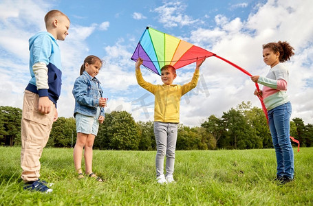 童年，休闲和人的概念—一群快乐的孩子在公园玩风筝。快乐的孩子与风筝玩在公园