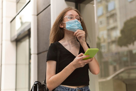 一名妇女在户外戴着医用口罩检查她的手机