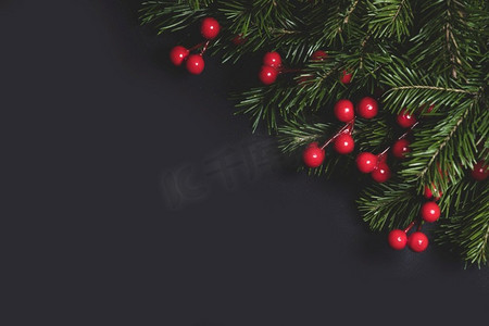圣诞边框用新鲜的冷杉树枝和红色浆果排列在黑色纸张背景上，文字复制空间。圣诞冷杉树枝和浆果