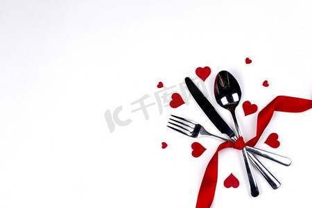 餐具套与丝带和心脏隔绝在白色背景情人节晚餐概念。餐具套装和心形